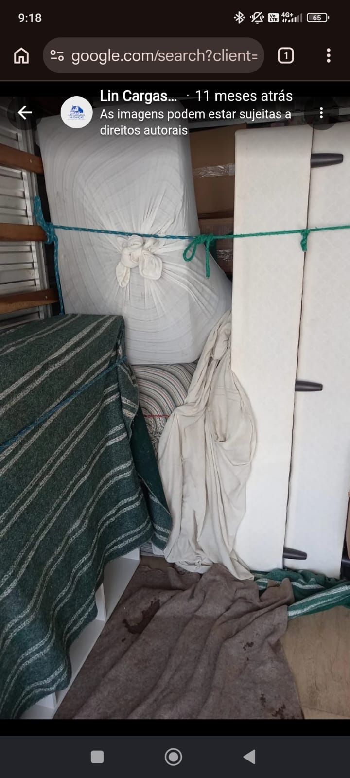 Colchão embrulhado em tecido branco e preso com corda verde dentro do baú, ao lado de móveis cobertos com manta listrada